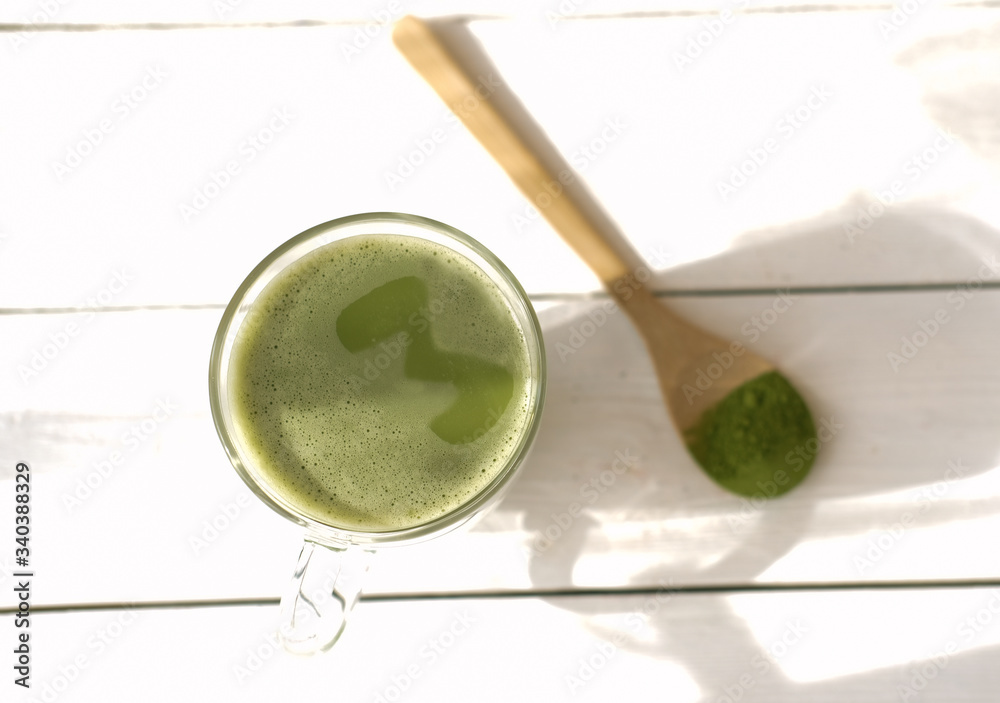 matcha latte in a mug and matcha powder in wooden spoon. healthy drinks concept. modern fashionable drink for weight loss and energy boost. top view