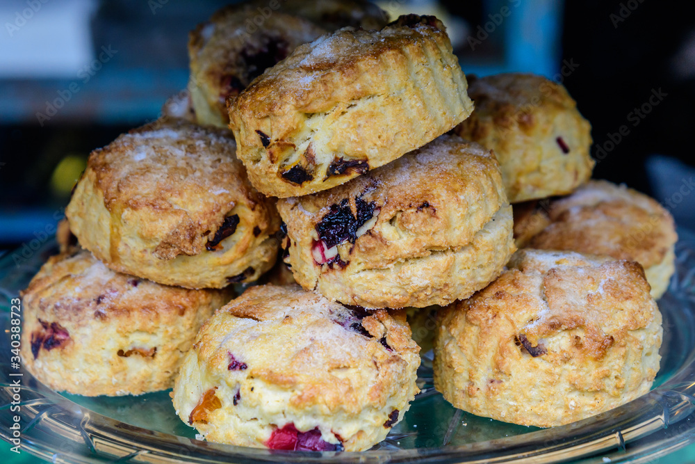 Freshly baked homemade English scones with dried fruits, displayed as a pyramid, available for sale at a café in London, side view of healthy food photographed with soft focus
