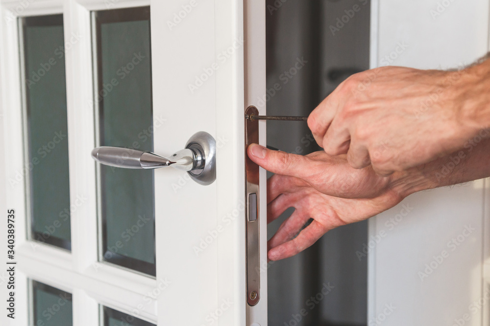 Male handyman carpenter at interior wood door lock installation Male handyman carpenter at interior wood door lock installation