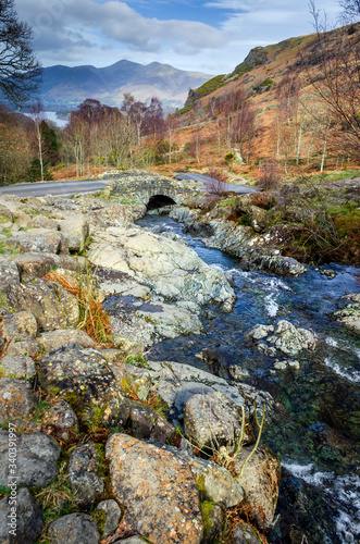 A view of the traditional stone Ashness Bridge in Borrowdale showing the water flowing down to Derwent water Keswick. .
