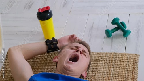 Funny sleepy lazy athlete yawning lying on the floor
