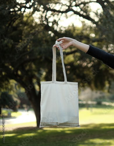 woman carry the re useable plastic free bag. eco friendly and sustainability life. hipster and minimal lifestyle to save the green earth and environment . trees background. photo