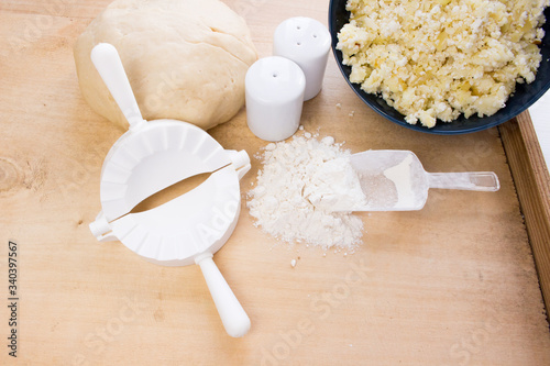 National Russian cuisine. Pierogi or pyrohy, vareniki, served with cottage cheese and potatoes on board.  Raw dumplings made of dough in handmade flour photo