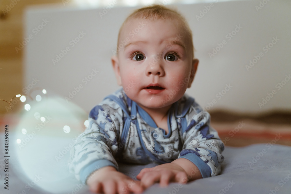 the baby is lying on its tummy and looks into the camera with wide open, clean, naive eyes the baby is lying on its tummy and looks into the camera with wide open, clean, naive eyes