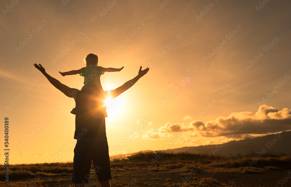 Happy father and son adventure outdoors in nature feeling free with arms in the air facing the sunset. 