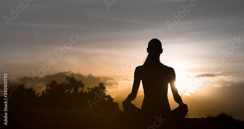Young woman relaxing sitting watching the sunrises. People at peace in nature. 