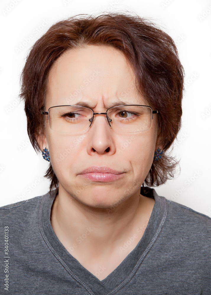 Portrait of a sad woman with glasses and short hair on a white background.