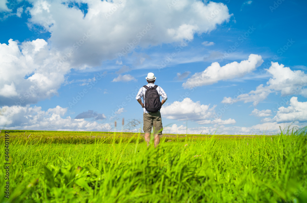 alone backpacker walking in a open field a beautiful sunny summer day. 