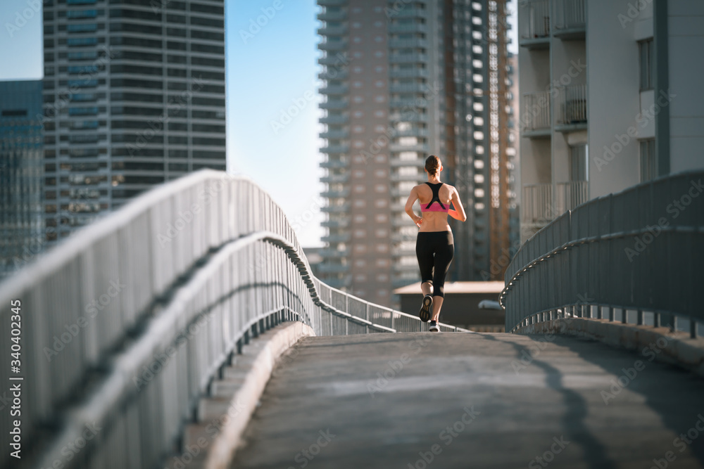 Female running across city bridge. Active healthy lifestyle 