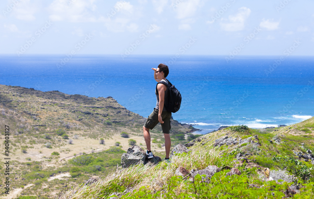 Young fit male hiker on top of mountain looking out at the view. Location Hawaii