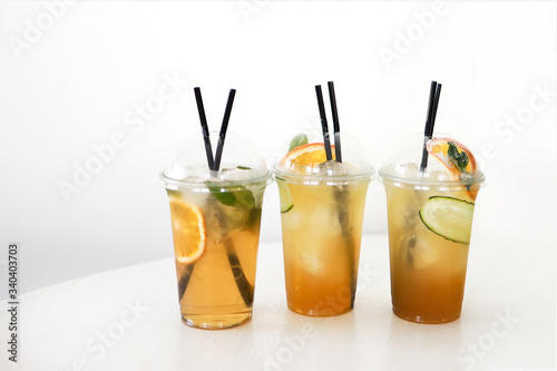 three lemonades, ice tea, on white table in plastic cups, take away, food delivery