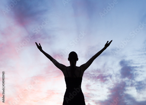 Young woman with arms up to sunset sky feeling happy, energized and rejuvenated. 