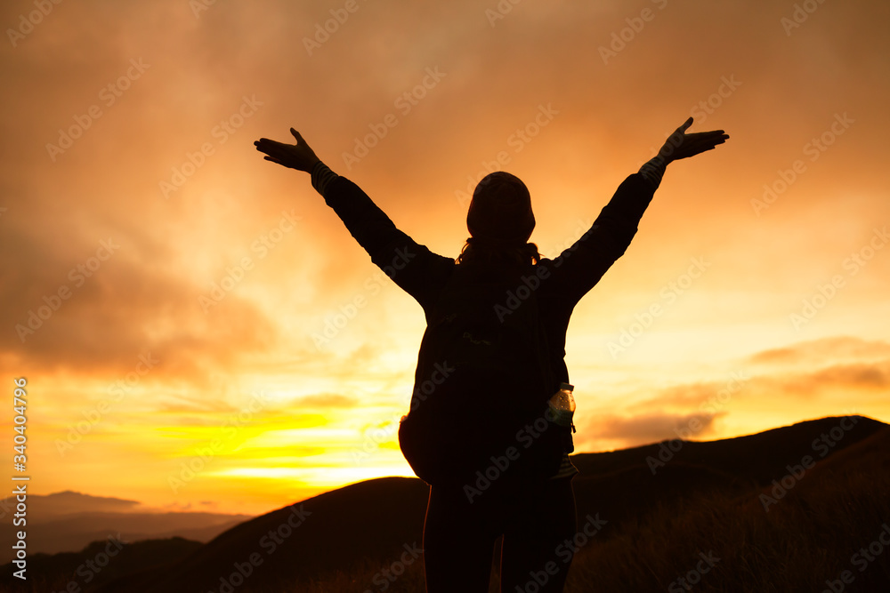 Happy young woman celebrating on top a mountain. 
