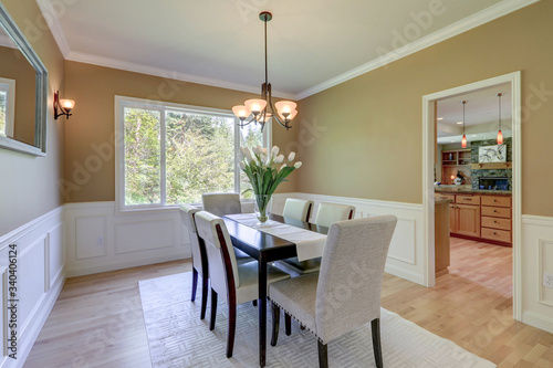 Classic elegant mustard color and grey tones dining room with large table and linen chairs.