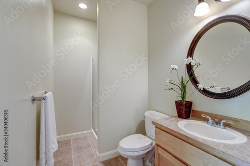 Simple bathroom interior with round metal mirrow and white sink and toilet  guest bedroom.