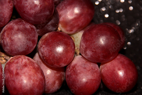 Large pink grapes on a black shiny background.