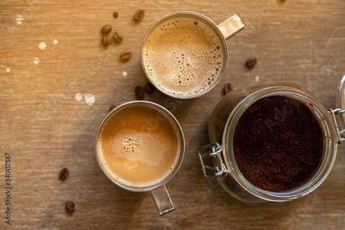 Canvas Print Coffee with milk in metal cups on a wooden table, top view