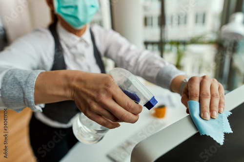 Close-up of businesswoman disinfecting her desktop PC in the office.