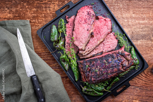 Traditional Commonwealth Sunday roast with sliced cold cuts roast beef with herbs and chili as top view on a modern design tray