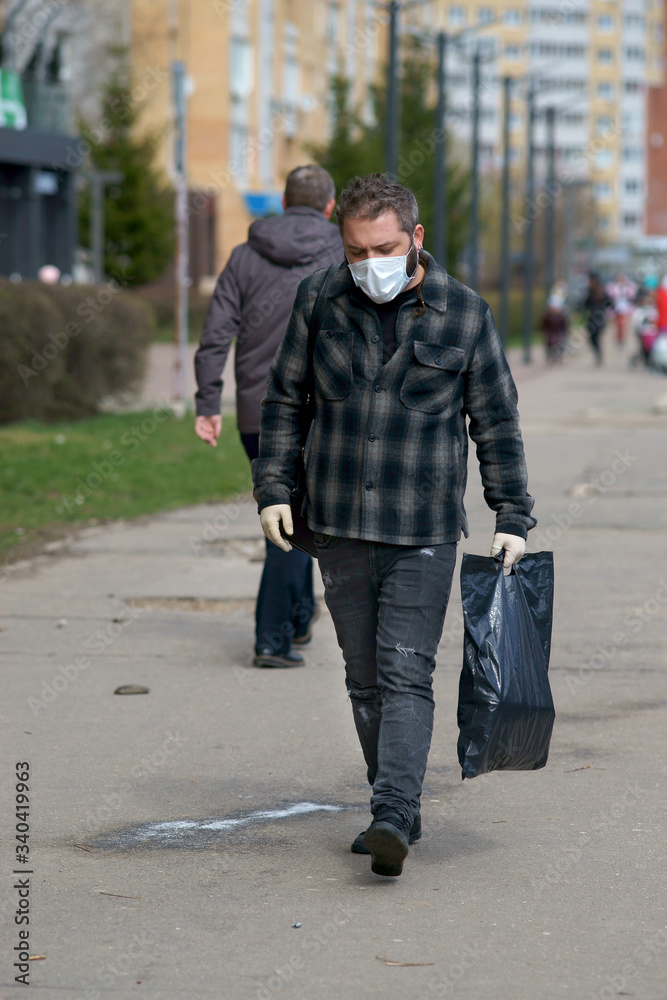 a man in a medical mask on the street, with bags a man in a medical mask on the street, with bags