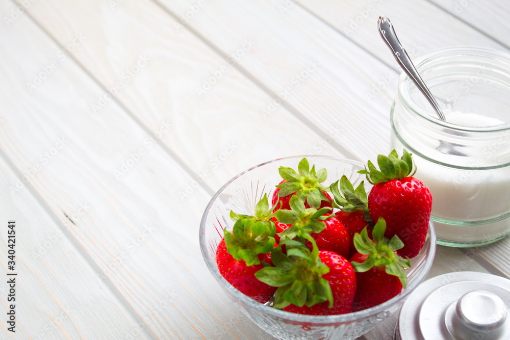 delicious red strawberries next to bowl with sugar and a spoon delicious red strawberries next to bowl with sugar and a spoon