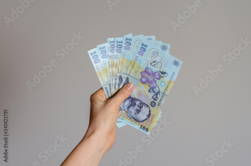 Wallpaper Mural Close up view of a woman's hand holding a pile of Romanian lei  money on a gray background . The economic impact of coronavirus  in  est Europe countries . Torontodigital.ca