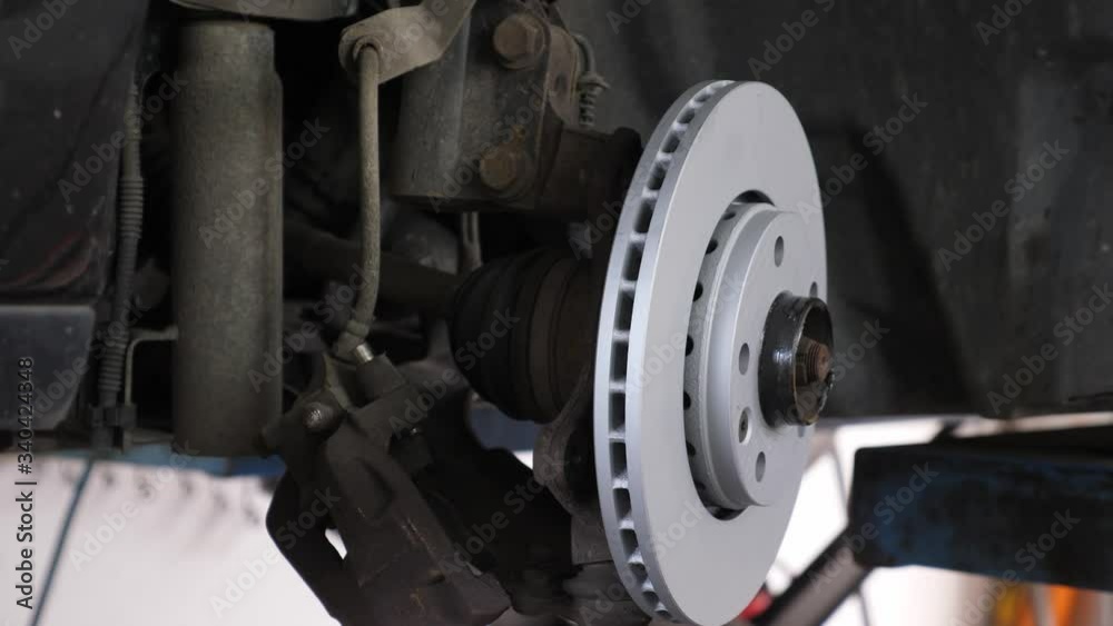 A moving shot at a car mechanic showing new disc brakes-backing plates and brake pads on a car