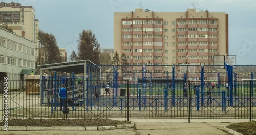 Timelapse of an urban city, a sports basketball and volleyball court, fields with children, sports equipment, residential buildings on a summer sunny day with the movement of clouds in the sky. photo