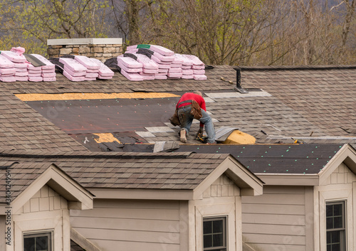 Foto Roofing contractor removing the old tiles before replacing with new shingles on