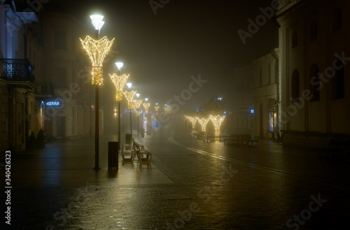 Night view of the colorful streets of the city during dense fog and smog. Winter season, Christmas time with colorful illuminations on the streets. Lublin, Poland, Europe.