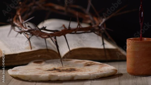 Wine Being Poured into Cup with Thorn Crown, Bible, and Bread in the background