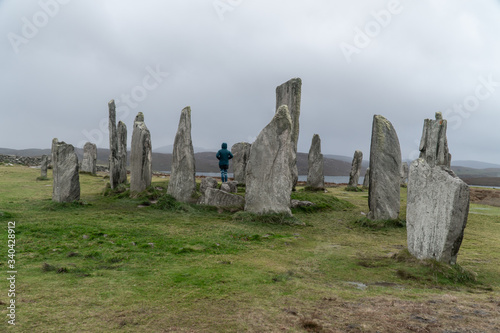 Girl, traveler stainding inside the Calanais Standing Stones in Outer Hebrides, Isle of Lewis, Scotland, UK. Moody and rainy weather. photo