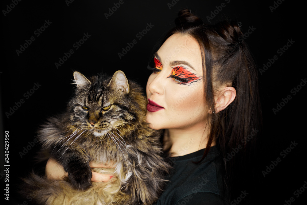 Fashion beauty portrait of a beautiful young girl. Makeup cat. Sexy woman with koshachmi ears on the hair. Face of the beautiful woman with long brown hair posing at studio over dark background. Fashion beauty portrait of a beautiful young girl. Makeup cat. Sexy woman with koshachmi ears on the hair. Face of the beautiful woman with long brown hair posing at studio over dark background.