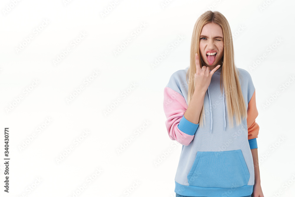 Sassy good-looking blonde teen girl having fun on party, enjoying awesome music, festival or cool event, wink daring and show tongue, make rock-n-roll sign, standing white background Sassy good-looking blonde teen girl having fun on party, enjoying awesome music, festival or cool event, wink daring and show tongue, make rock-n-roll sign, standing white background