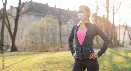 Fit woman during health crisis exercising outdoors wearing mask