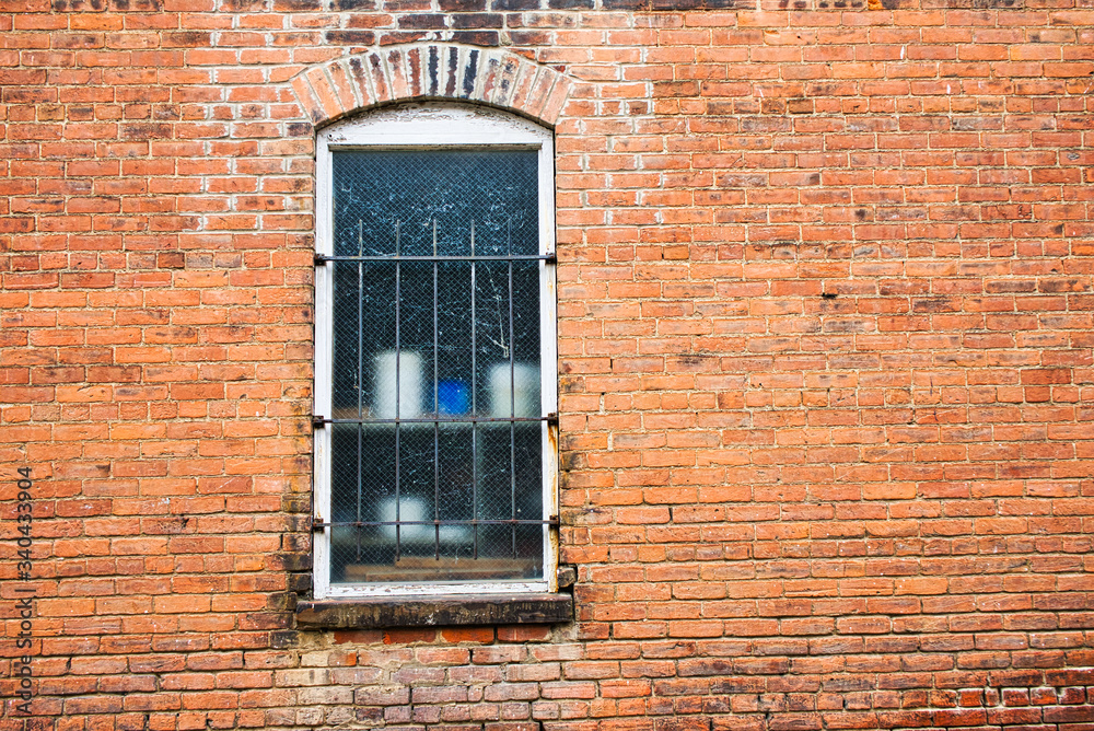 Brick wall with window with old crock type pots on shelf 