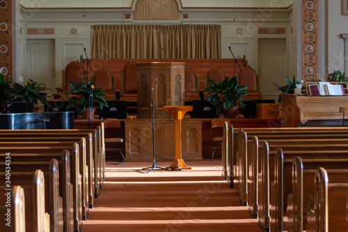 medium wide shot of an empty church sanctuary with afternoon sunlight pouring in creating shadows down the aisle to the front of the church 