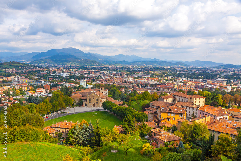Aerial view of Bergamo city, Lombardy, Italy. Bergamo Alps (Alpi Orobie) begin immediately north of the city, on the background. Picturesque autumn view