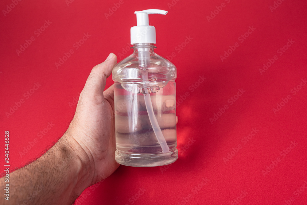 Man hand in container with alcohol gel on the red background Man hand in container with alcohol gel on the red background