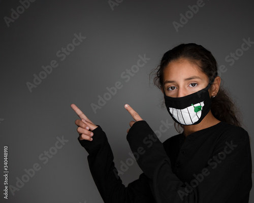 Girl with mask social distancing pointing at open space