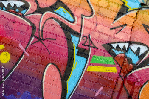 Abstract colorful fragment of graffiti paintings on old brick wall. Street art composition with parts of unwritten letters and multicolored stains. Subcultural background texture photo