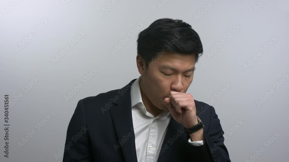 Smartly dressed Asian man coughing into hand Smartly dressed Asian man coughing into hand