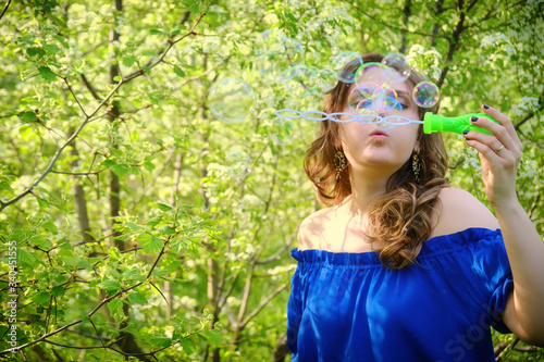 A young woman lets soap bubbles on the background of a flowering tree  copy space for text