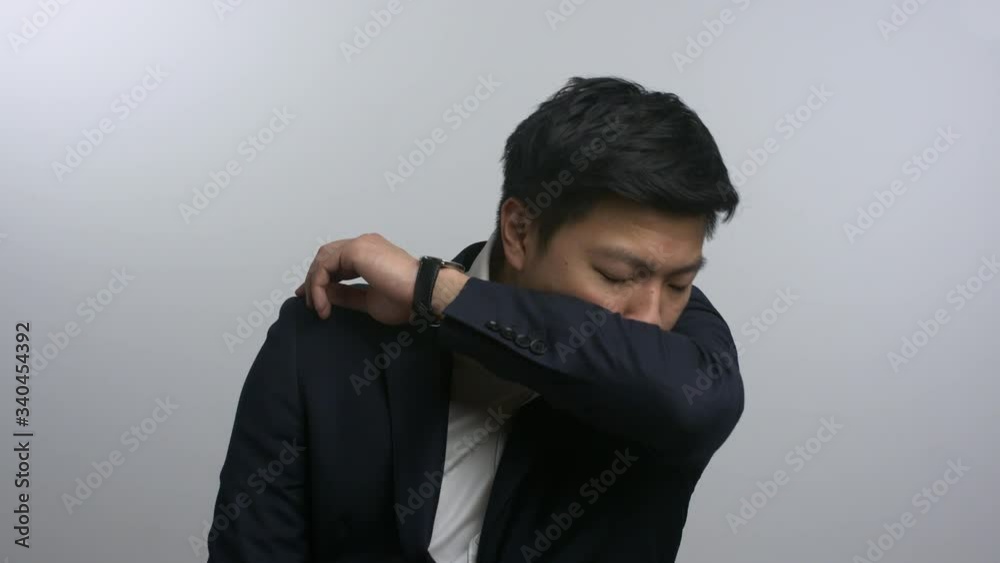 Smartly dressed Asian man coughing into elbow Smartly dressed Asian man coughing into elbow