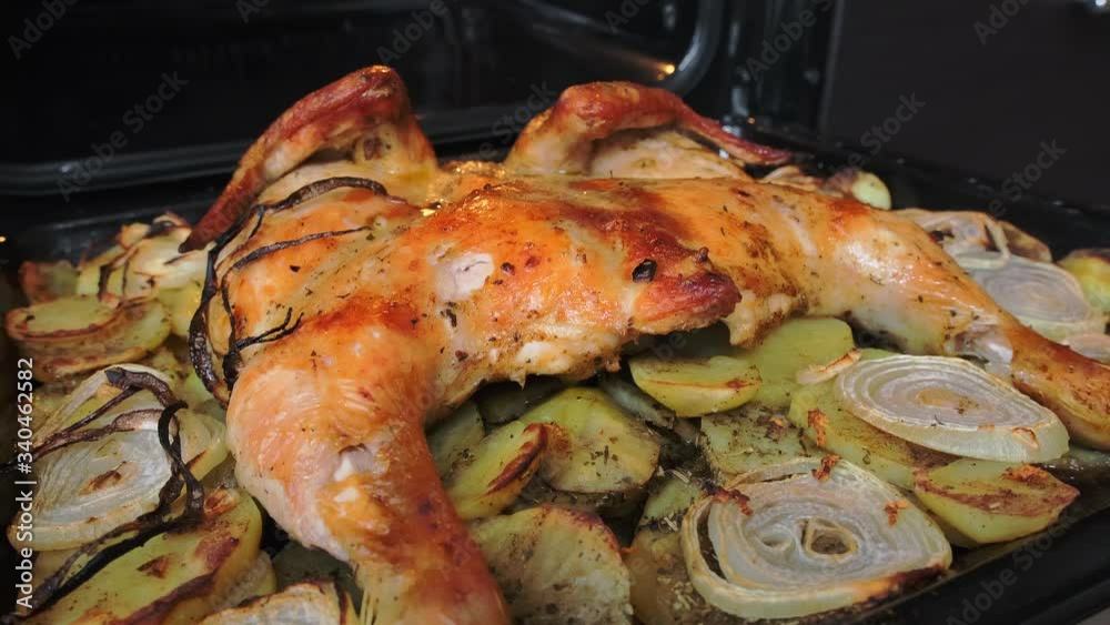 Fried chicken with spices and potatoes on a baking sheet is fried in the oven Fried chicken with spices and potatoes on a baking sheet is fried in the oven