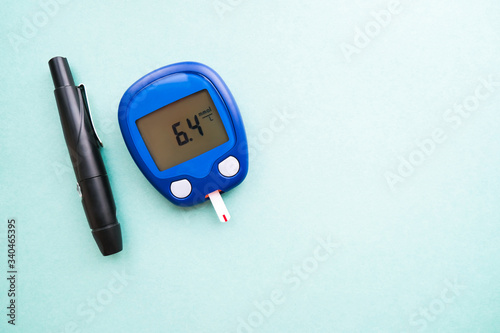 Glucometer with test strip and lancelet on blue background. Blood glucose meter. Copy space. Diabetes concept. photo