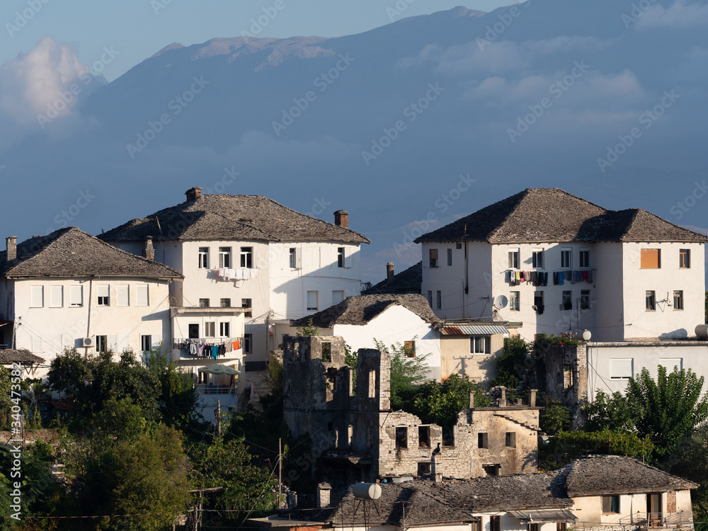 White stucco and slate-roofed Ottoman Houses in Gjirokaster, Albania with a mountain in the background. 