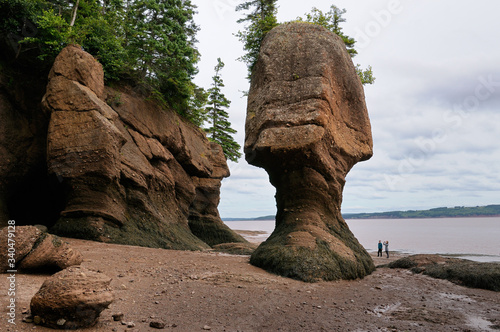 Two tourists looking at Mother in law flower pot sea stack at Hopewell Rocks Bay of Fundy
