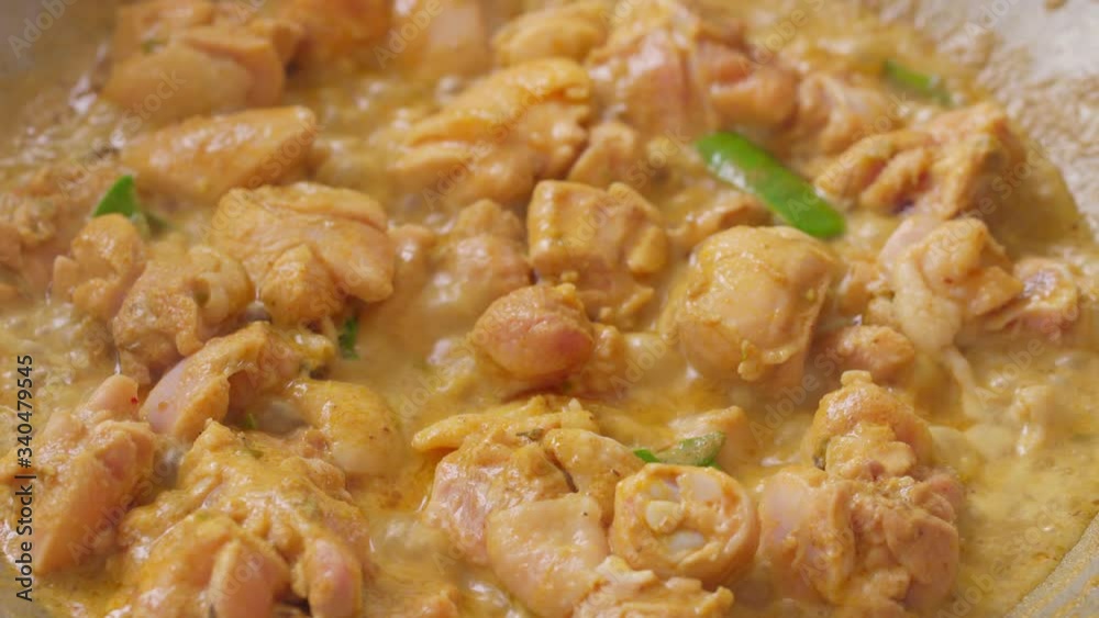 A person is cooking a Thai Spicy Green Curry with Chicken in the kitchen Closeup A person is cooking a Thai Spicy Green Curry with Chicken in the kitchen Closeup