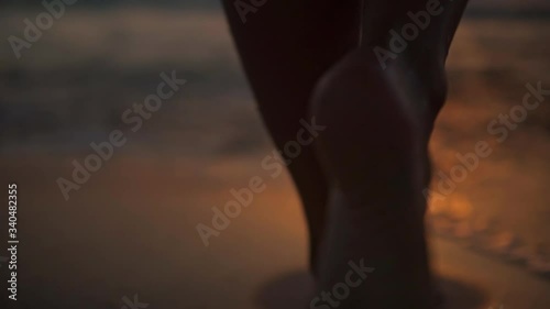 The feet of a young woman walking towards the sea at the first light of dawn, in the background the rising sun, full hd slow motion video